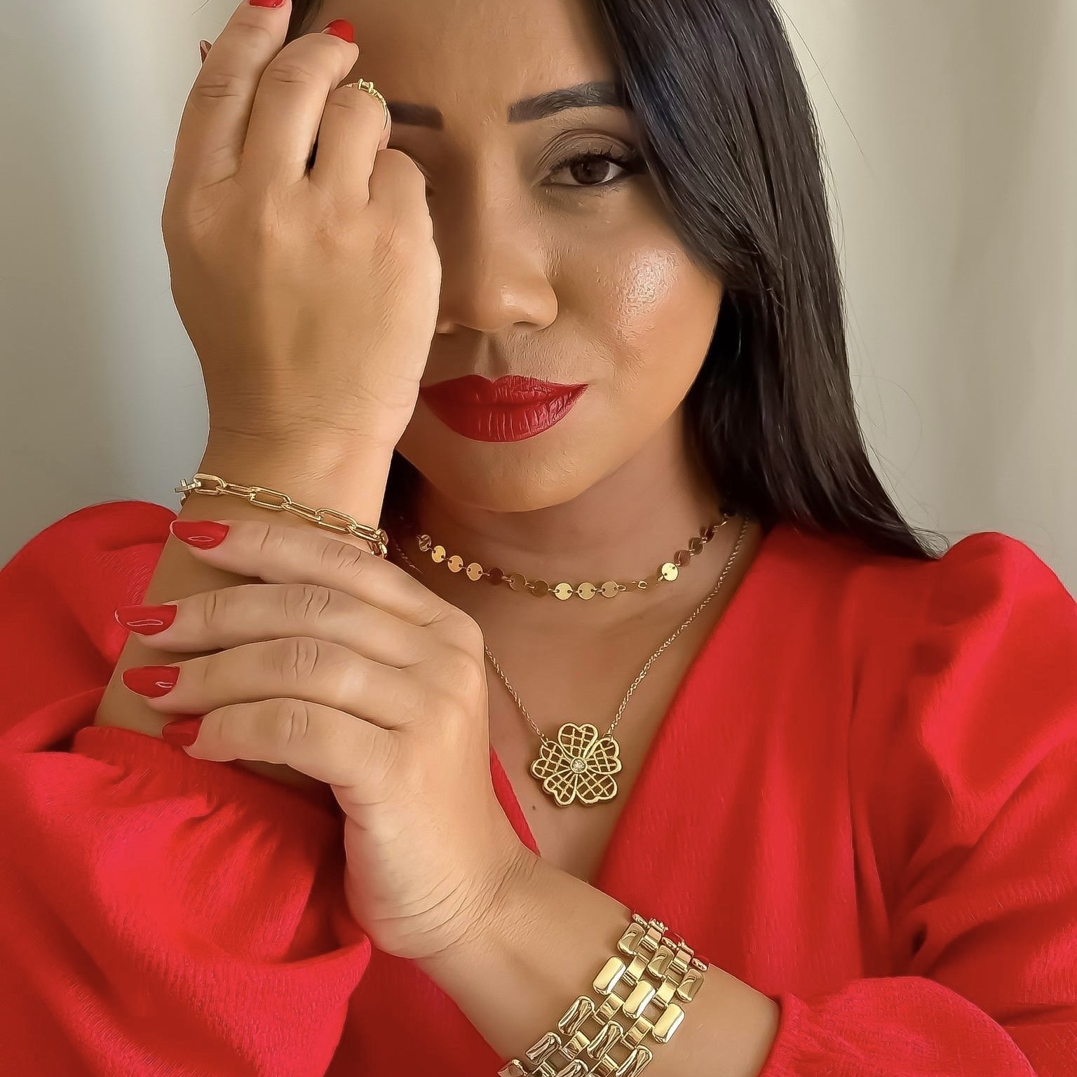 Proprietária da Amaly usando acessórios dourados com look vermelho.