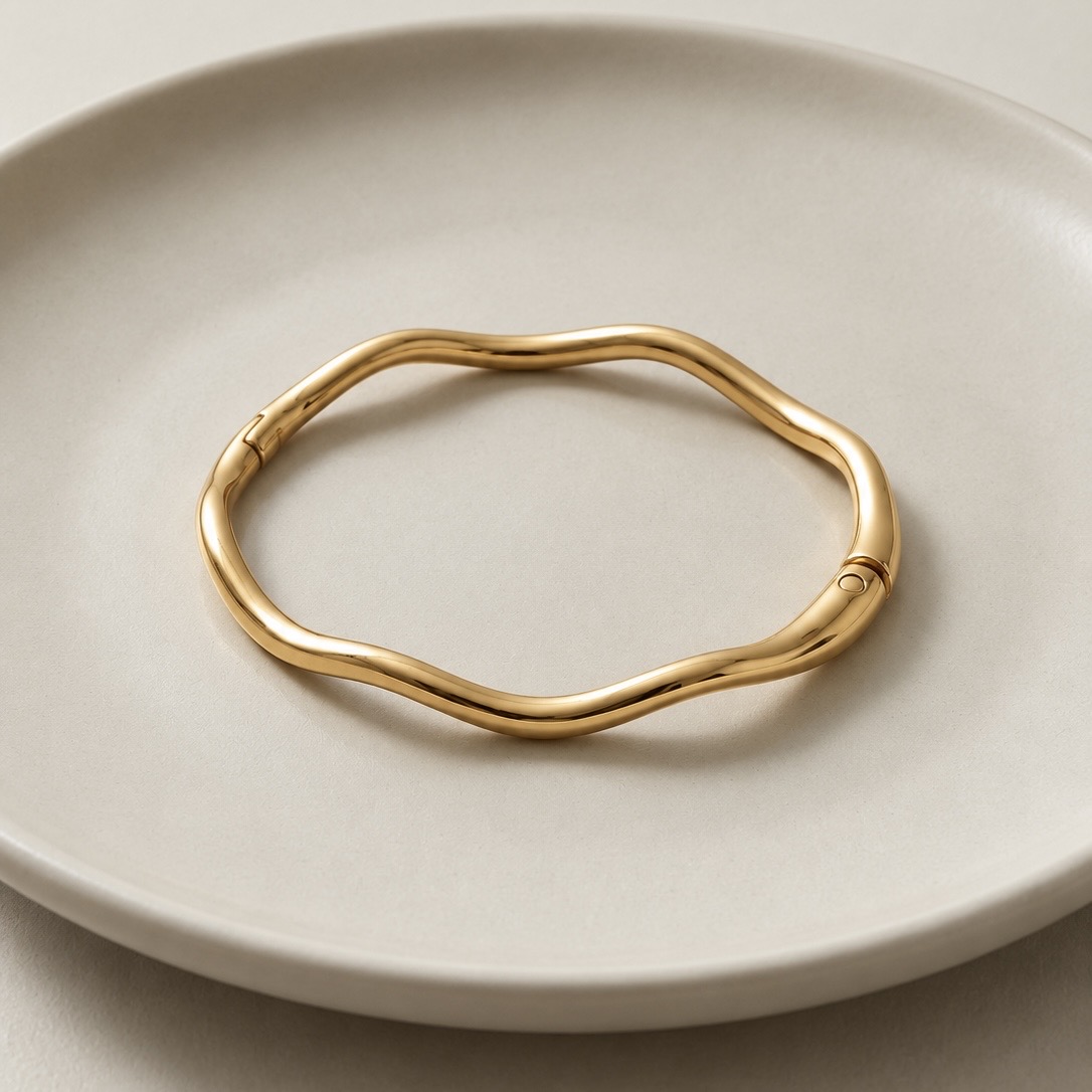 Bracelete ondulado na cor ouro sobre prato neutro