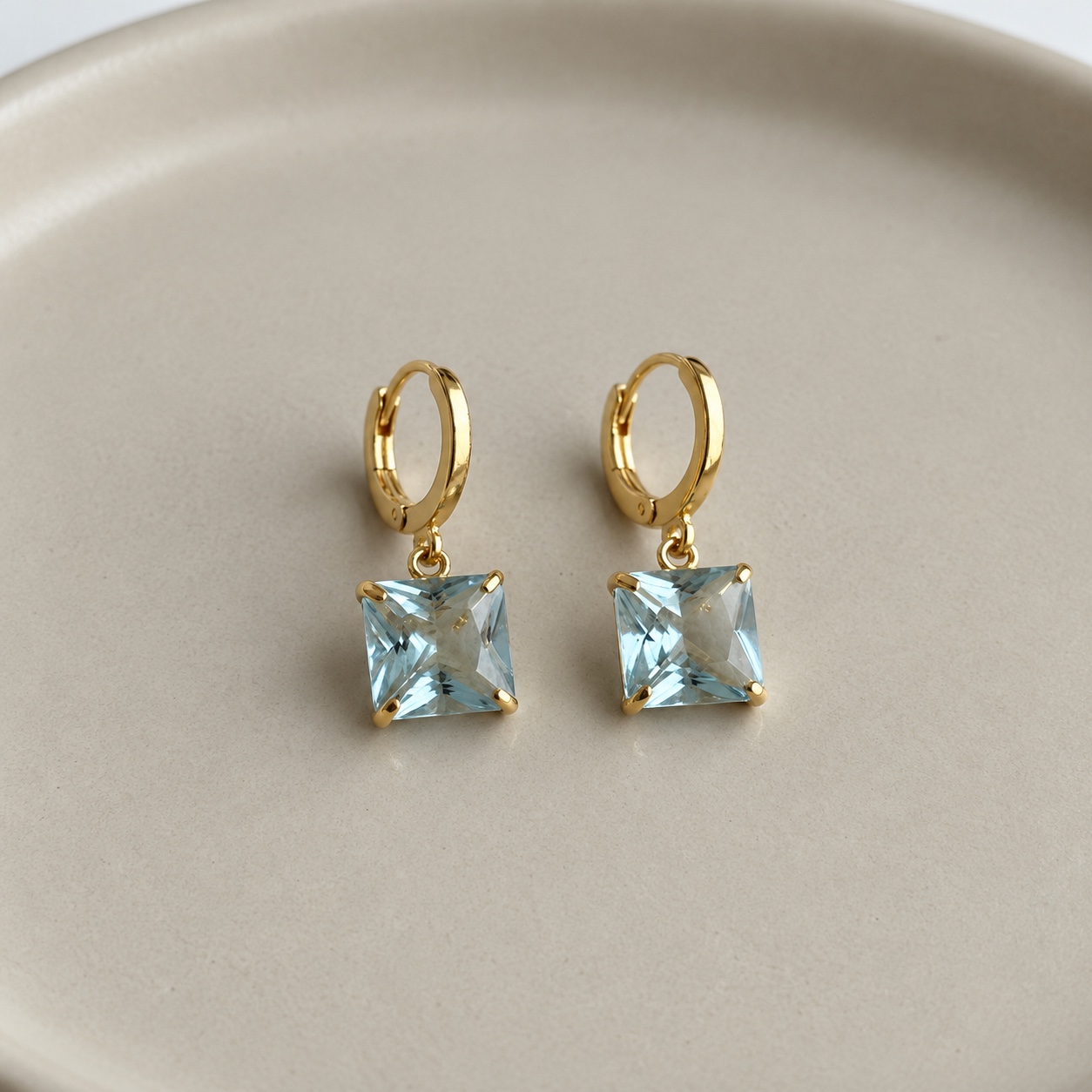 Par de brincos argola dourados com cristal azul quadrado