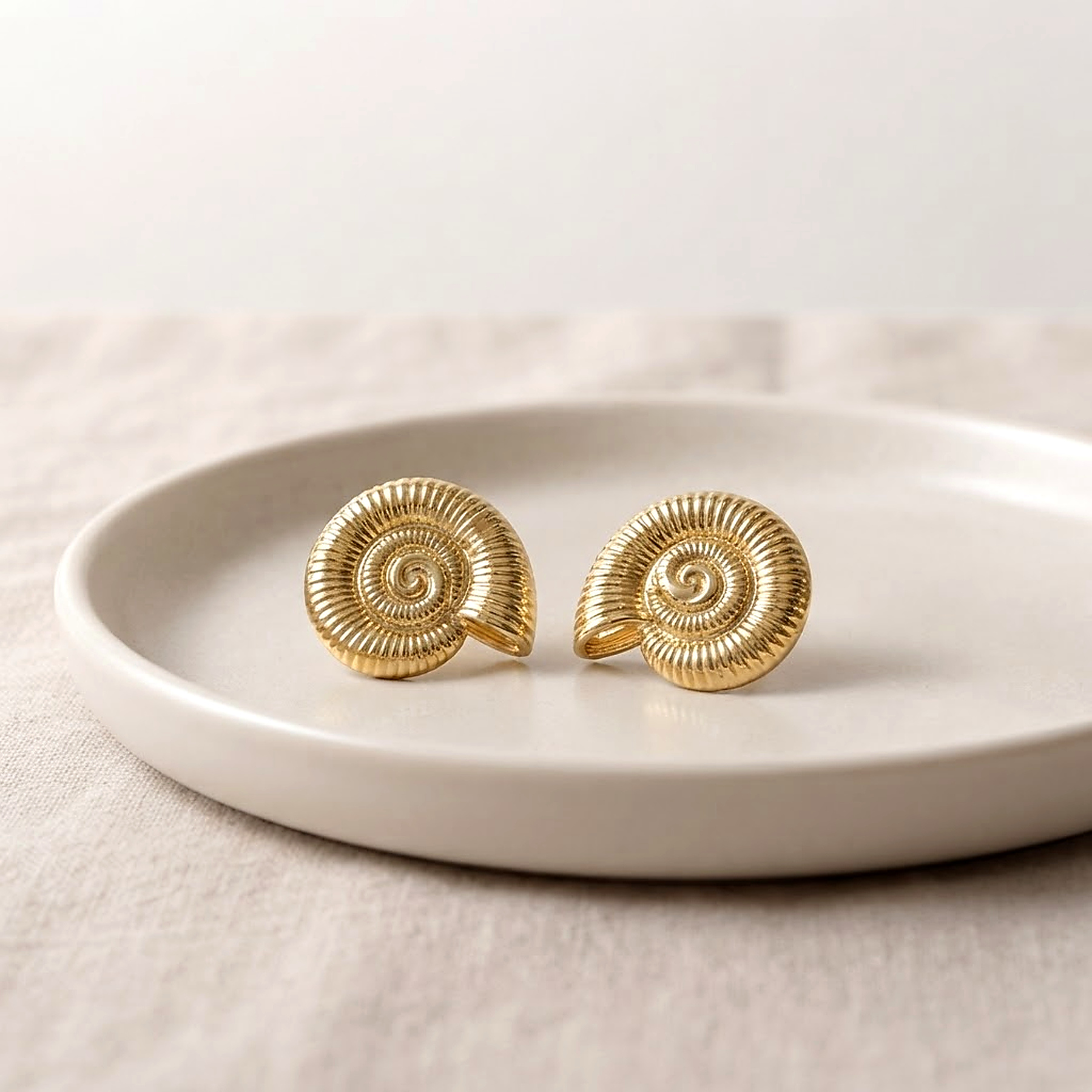 Par de brincos dourados em formato de caracol