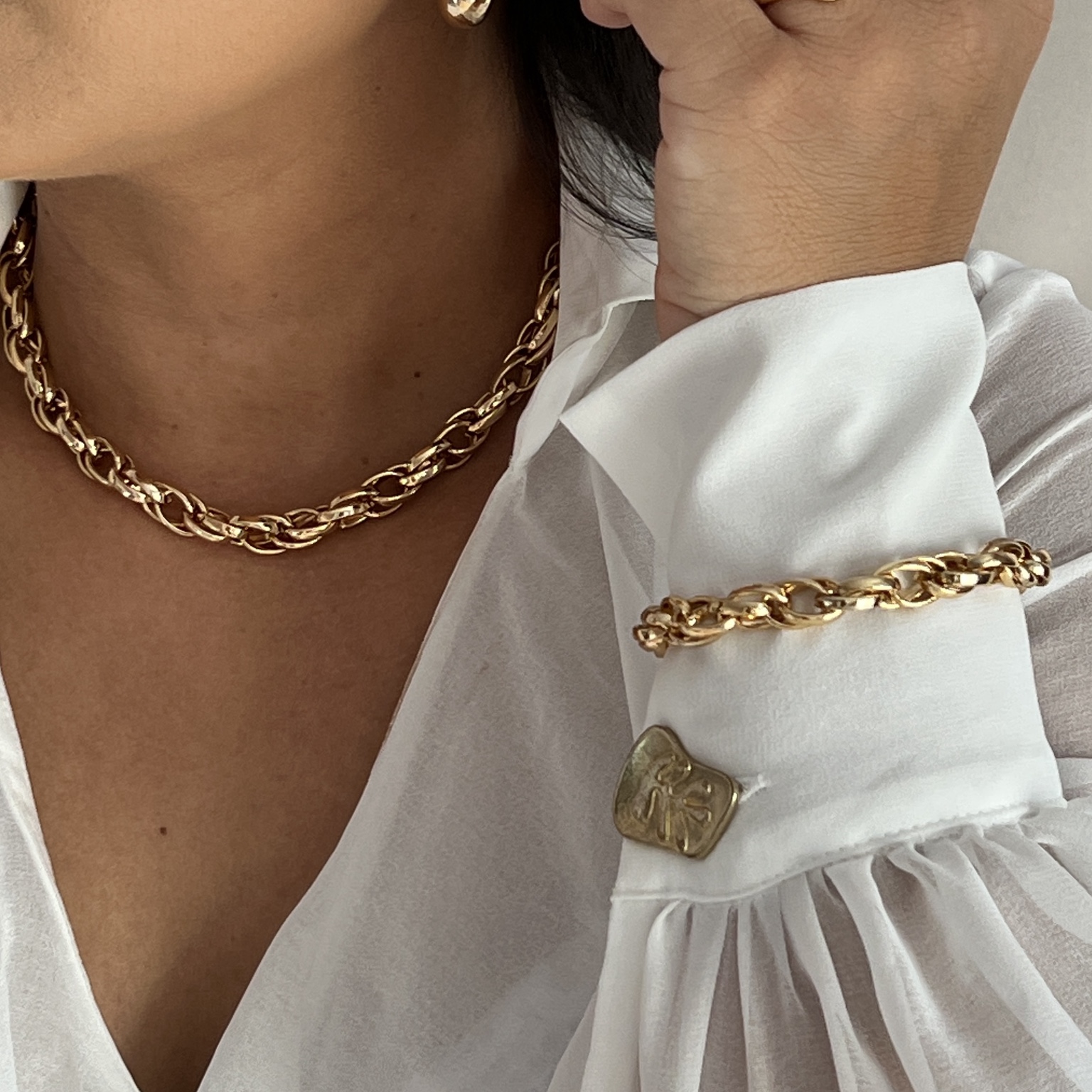 Modelo usando conjunto dourado de colar e pulseira com elos trançados